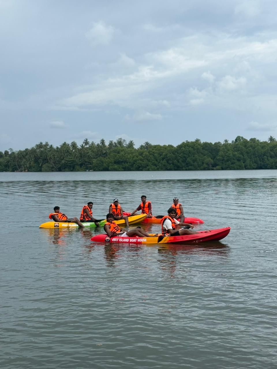 A group of paddlers in orange life jackets rafted together on Visit Island Boat House kayaks