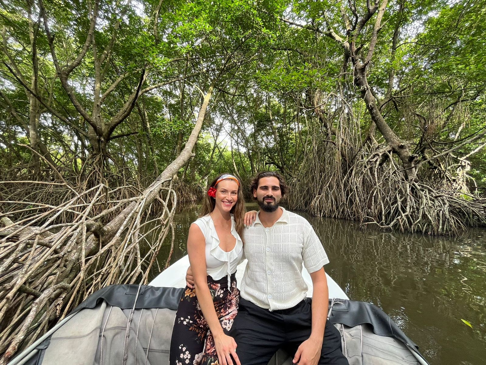 A couple smiling at the bow of a safari boat inside a mangrove tunnel on the Bentota River